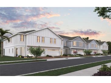 Two-story townhouses with modern farmhouse exterior, two-car garages, and landscaping at 164 Glass Onion Dr, Groveland, FL 34737