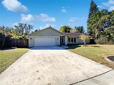 House exterior featuring a light-grey facade, white garage door, and a well-maintained lawn at 4026 Tenita Dr, Winter Park, FL 32792