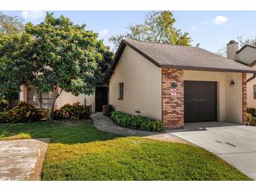 Brick front exterior of a condo with a one car garage and well manicured landscaping at 175 Golf Club Dr # 175, Longwood, FL 32779