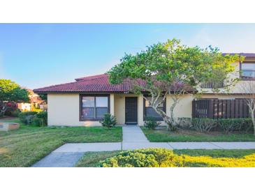 Inviting exterior of a condo with a tiled roof, landscaping, and a walkway at 547 Hunter Cir # 547, Kissimmee, FL 34758