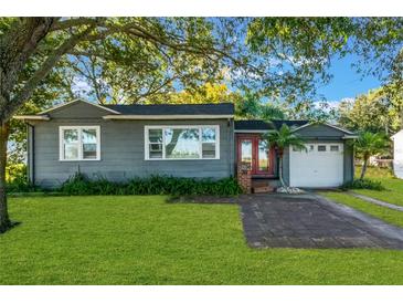 Gray house with a white garage, red door and nicely landscaped lawn at 20 Maynard Ave, Orlando, FL 32803