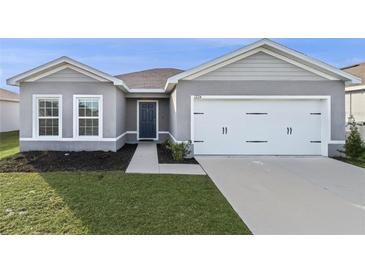 Gray house with white garage door and dark blue front door at 1224 Golden Eagle Ln, Winter Haven, FL 33880
