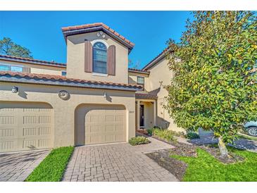 Tan two-story townhome with two-car garage and landscaping at 8169 Roseville Rd, Davenport, FL 33896