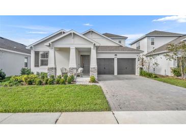 Two-story home with gray two car garage and landscaped front yard at 4473 Davos Dr, Clermont, FL 34711