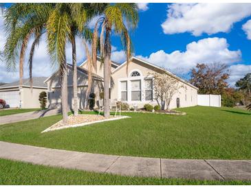 Tan house with palm trees, two-car garage, and manicured lawn at 1645 Stefan Cole Ln, Apopka, FL 32703