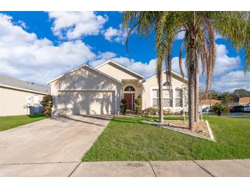 Tan house with a two-car garage and palm trees in the front yard at 1645 Stefan Cole Ln, Apopka, FL 32703