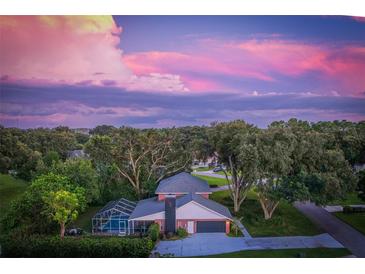 Aerial view of house, pool, and landscaped yard at sunset at 116 Reflection Blvd, Auburndale, FL 33823