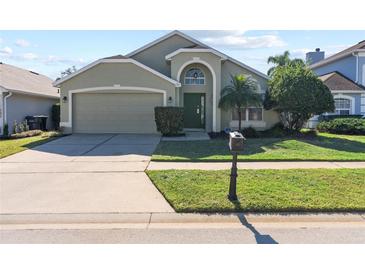 Two-story house with a green exterior, two-car garage, and a well-maintained lawn at 422 Troon Cir, Davenport, FL 33897