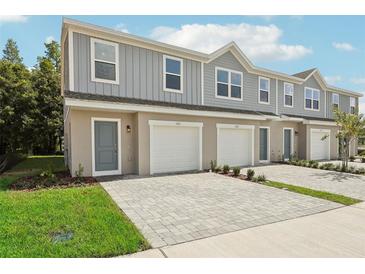 Three-unit townhome building with gray siding, attached garages, and paved driveways at 1215 Fan Palm Dr, Davenport, FL 33897