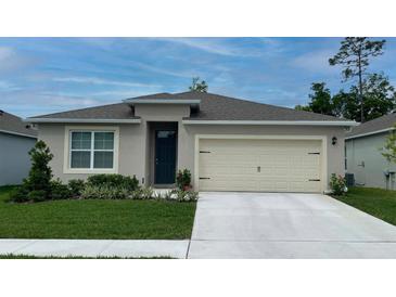 One story home with beige exterior, two car garage, and landscaped lawn at 2121 Pigeon Plum Dr, Haines City, FL 33844