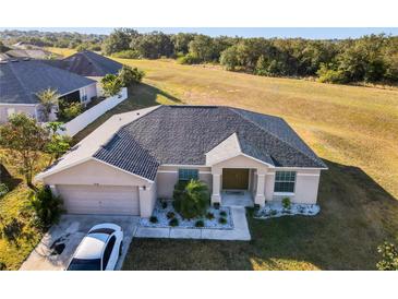 One-story house with gray roof, landscaping, and a driveway at 1218 Coda Ct, Dundee, FL 33838