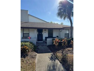 Bright white exterior of a condo with a walkway and tropical landscaping at 2810 Plaza Terrace Dr # 2810, Orlando, FL 32803