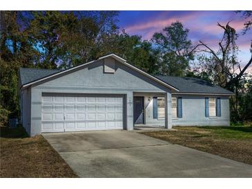 Gray house with white garage door and blue shutters, at dusk at 1073 Humphrey Blvd, Deltona, FL 32738