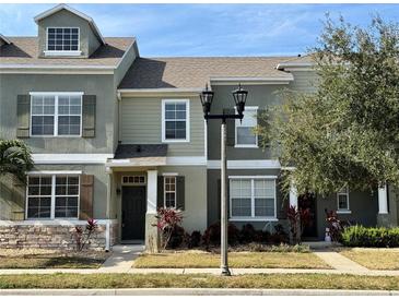 Two-story townhome with green siding, dark shutters, and a welcoming front entrance at 1618 J Lawson Blvd, Orlando, FL 32824