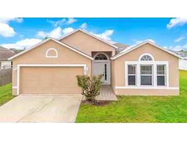 Tan, single-story home with attached two-car garage and landscaped front yard at 2410 Hatton Chase Ln, Kissimmee, FL 34746