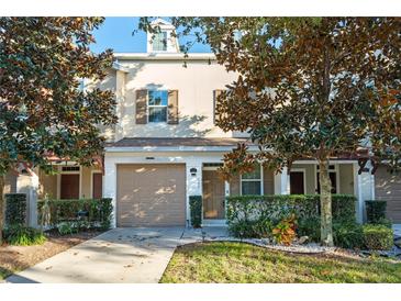 Tan two-story townhome with attached garage and landscaping at 659 Fortanini Cir, Ocoee, FL 34761