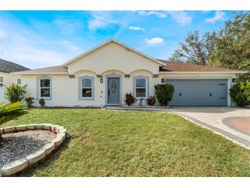 One-story house with a gray door, attached garage, and well-manicured lawn at 1812 Hudson Ct, Kissimmee, FL 34759