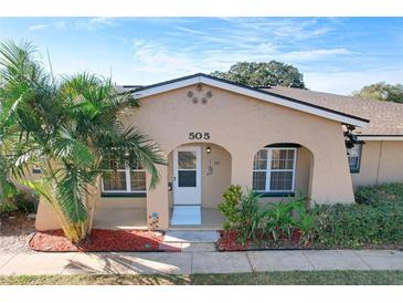 Tan house with a white door, palm trees, and red mulch at 505 Polaris Loop # 107, Casselberry, FL 32707
