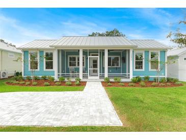 Charming light teal cottage with metal roof, screened porch, and paved walkway at 12071 Lakeshore Way, Oxford, FL 34484