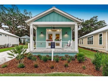 Charming cottage with light teal exterior, front porch, and landscaping at 12133 Grand Oak Ln, Oxford, FL 34484