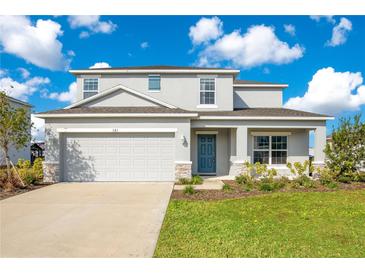 Two-story house with gray siding, two-car garage, and landscaped yard at 381 Citrine Loop, Kissimmee, FL 34758