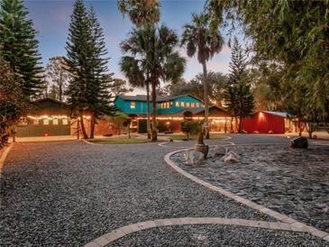 Charming front yard with string lights, gravel driveway, and lush landscaping at 6320 Rocky Point Rd, Lake Wales, FL 33898