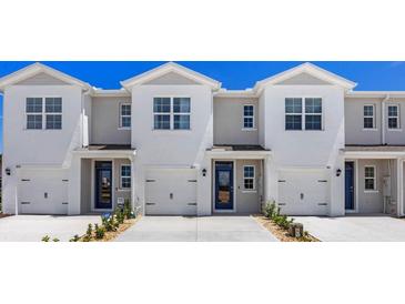 Three-unit townhome building with modern design and attached garages at 1210 Balsam Dr, Davenport, FL 33837