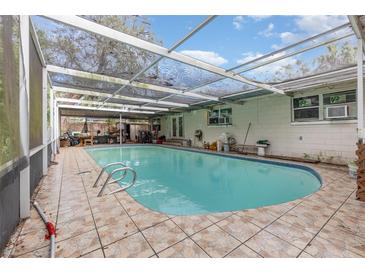 Large kidney-shaped pool with tile decking and covered patio at 2900 Woodbridge Ln, Orlando, FL 32808