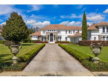 Grand two-story home with tile roof, stone accents, and manicured landscaping at 9343 Tibet Pointe Cir, Windermere, FL 34786