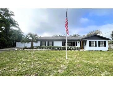 Newly renovated home with white exterior, landscaping, and American flag at 1625 Normandy Way, Leesburg, FL 34748