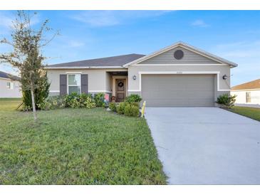 One-story house with gray siding, two-car garage, and landscaped front yard at 2325 Crossandra St, Mascotte, FL 34753