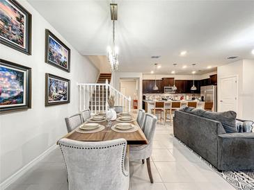 Bright dining room features a wood table, and gray upholstered chairs, with a view of the kitchen at 4190 Lana Ave, Davenport, FL 33897