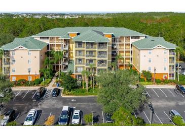Exterior elevation of a multi-story condominium building with balconies, surrounded by parking and landscaping at 9051 Treasure Trove Ln # 102, Kissimmee, FL 34747