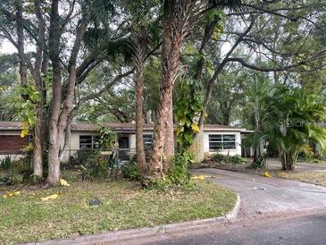Front exterior view of a single-story home with a driveway, landscaping, and trees at 826 Rosalia Dr, Sanford, FL 32771