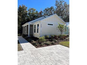 Charming beach house with landscaped yard and paved walkway at 12143 Grand Oak Ln, Oxford, FL 34484