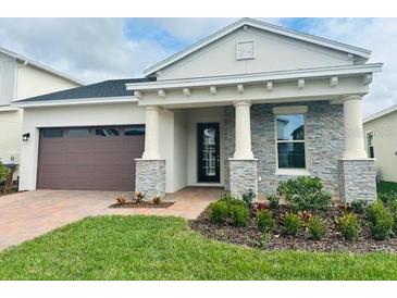 One-story home with gray stone accents and a brown garage door at 2813 Willowseed Ln, Saint Cloud, FL 34772