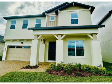 Two-story house with a beige exterior, landscaped yard, and two-car garage at 4946 Shady Pines Dr, Saint Cloud, FL 34772