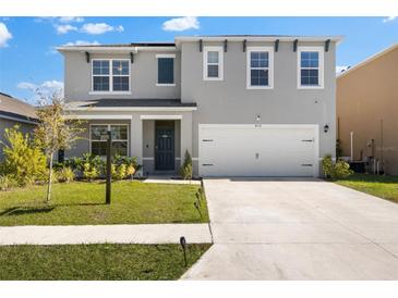 Inviting two-story home with a neat front lawn, driveway, and attached garage at 839 Sun Burst Rd, Winter Haven, FL 33880