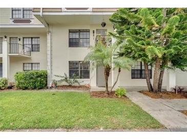 Front exterior view of a two-story condo with a green lawn and trees at 6030 Village Cir, Orlando, FL 32822