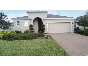 One-story house with beige exterior, two-car garage, and manicured lawn at 2393 Jernigan Loop, Kissimmee, FL 34746