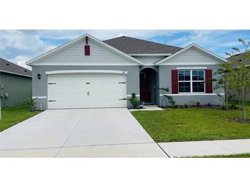 One-story home with gray siding, white garage door, and red shutters at 811 Turner Ln, Winter Haven, FL 33881
