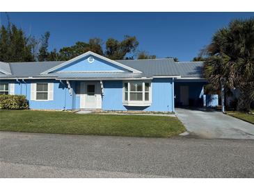 Cute light blue house with gray roof, driveway, and landscaped lawn at 11 Sandra Cir, New Smyrna Beach, FL 32168