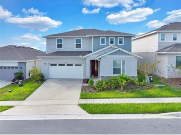 Two-story house with gray siding, red door, and a white garage door at 1128 Sugarwood St, Davenport, FL 33837