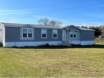 Gray manufactured home on a spacious lot with a well-maintained lawn at 18802 Merrich Rd, Orlando, FL 32820