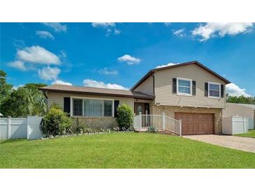 Two-story house with a beige exterior, a wooden garage door, and a well-maintained lawn at 610 Alton Rd, Winter Springs, FL 32708