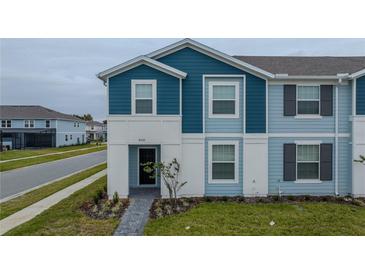 Two-story townhome with blue siding, a walkway, and landscaping at 4250 Lana Ave, Davenport, FL 33897