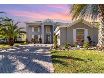 Two-story house with gray exterior, paver driveway, and lush landscaping at 9168 Lake Avon Dr, Orlando, FL 32829