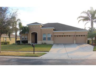 Tan two-story house with a three car garage and manicured lawn at 428 Palastro Ave, Auburndale, FL 33823