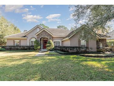 One-story home with stone accents, red door, and landscaped lawn at 25628 Hawks Run Ln, Sorrento, FL 32776