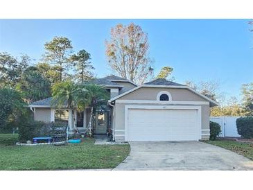 Tan house with white garage door and landscaped yard at 1022 Bartlett Ct, Oviedo, FL 32765